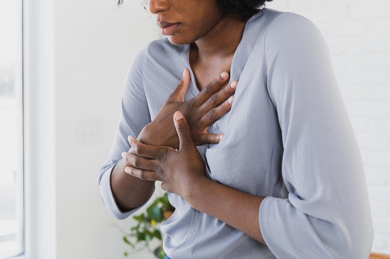 Frau hat Herzschmerzen und fasst sich an die Brust