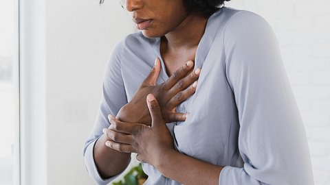 Frau hat Herzschmerzen und fasst sich an die Brust - Foto: iStock7SDI Productions