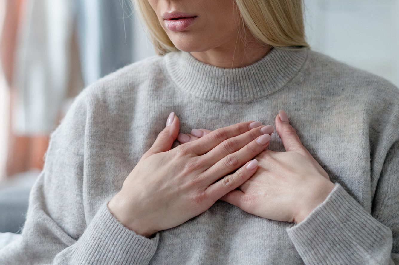 Frau mit Hinterwandinfarkt-Symptomen fasst sich an den Brustkorb