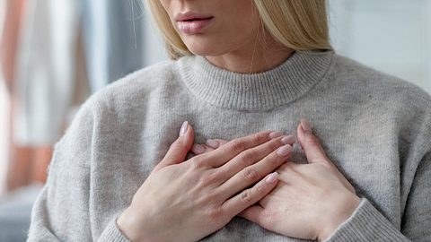 Frau mit Hinterwandinfarkt-Symptomen fasst sich an den Brustkorb - Foto: iStock/brizmaker
