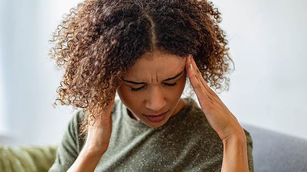 Eine Frau hält sich den Kopf - Foto: iStock/vitapix