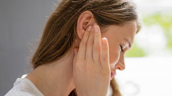 Frau hält sich das rechte Ohr - Foto: iStock/AndreyPopov