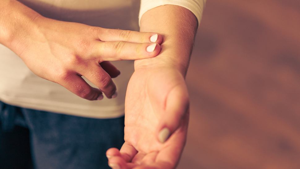 Frau überprüft Puls am Handgelenk - Foto: iStock/Voyagerix