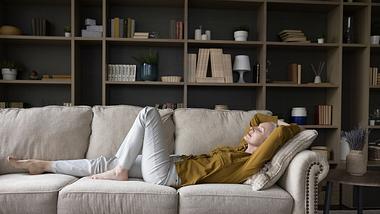 Frau liegt auf dem Sofa - Foto: iStock/fizkes