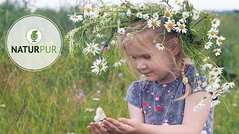 Kleines Mädchen mit Blumenkranz und Schmetterling auf der Hand - Foto: istock/kozorog