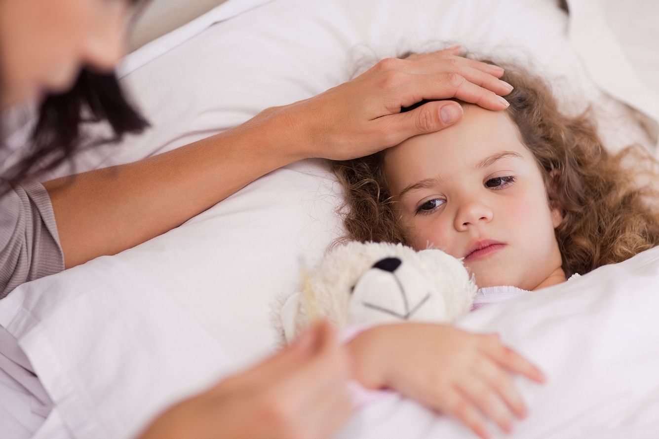 homoeopathie-bei-kindern Mutter legt die Hand auf die Stirn ihres erkälteten Kinds