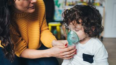 Mutter hält Kind Inhalationsmaske ins Gesicht - Foto: iStock/filadendron