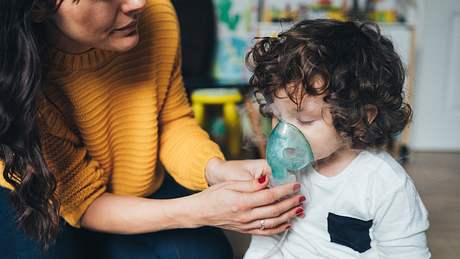 Mutter hält Kind Inhalationsmaske ins Gesicht - Foto: iStock/filadendron