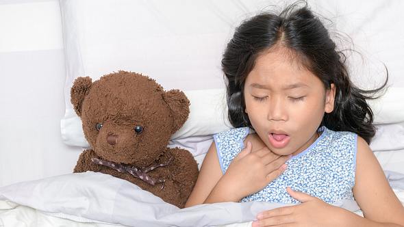 Mädchen liegt mit Teddy im Bett und hustet - Foto: iStock_kwanchaichaiudom