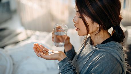 Eine Frau nimmt eine Tablette mit einem Glas Wasser - Foto: iStock/AsiaVision