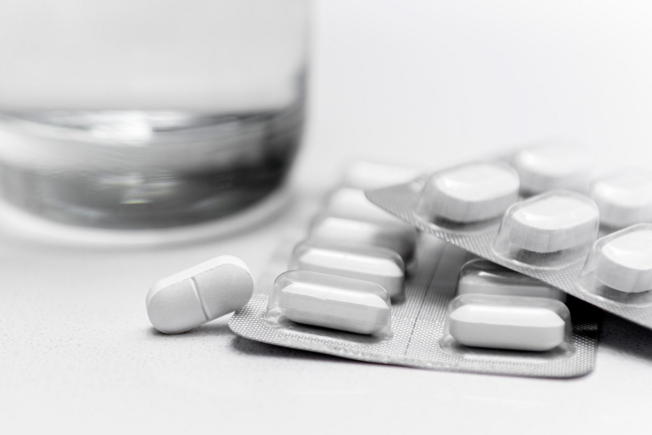 Blitser mit Tabletten, im Hintergrund ein Wasserglas