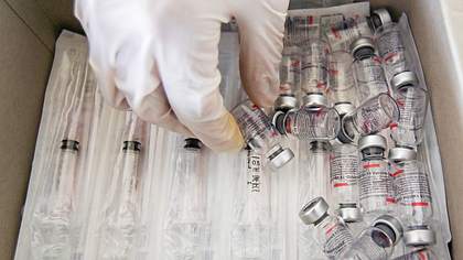 Eine Hand mit Schutzhandschuhen greift in Schublade mit Spritzen und leeren Impfstoff-Ampullen - Foto: IMAGO / Pacific Press Agency
