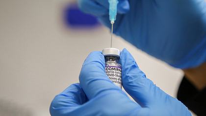Hände mit Schutzhandschuhen ziehen einen Impfstoff aus einer Ampulle in eine Spritze auf - Foto: IMAGO / ZUMA Wire
