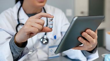 Ärztin checkt Tablet, Impfdosis in der Hand - Foto: iStock / doble-d