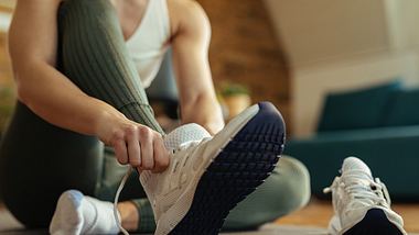 Frau zieht sich Schuhe zum Indoor Walking an - Foto: iStock/Drazen Zigic
