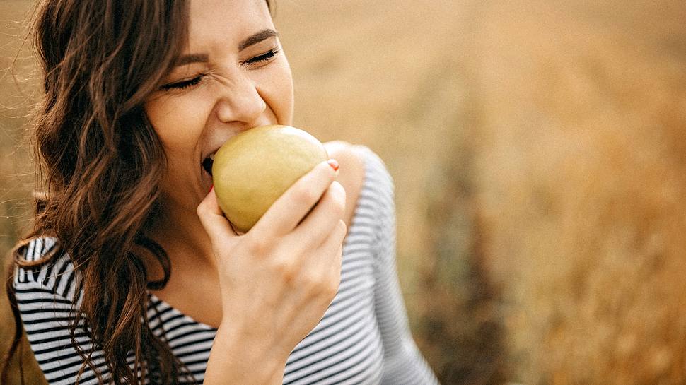 Frau beißt in einen Apfel - Foto: iStock/eclipse_images