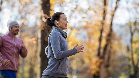 Ein Mann und eine Frau joggen im Wald - Foto: iStock_humanmade
