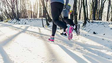 Jogger laufen auf einem verschneiten Waldweg - Foto: iStock-509796306 Georgijevic