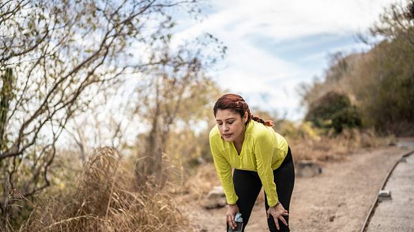 Frau macht beim Joggen eine Pause und stützt sich auf die Beine - Foto: iStock/FG Trade Latin