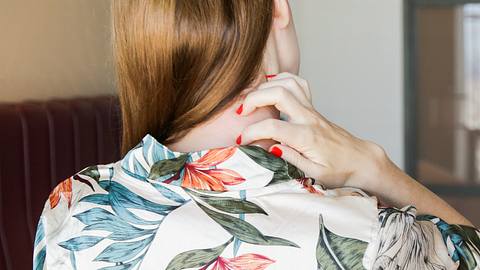 Eine Frau kratzt sich im Nacken - Foto: iStock/triocean
