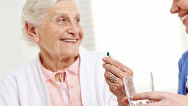 Eine junge Frau gibt einer alten Frau eine Tablette - Foto: Fotolia