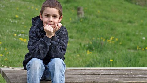 Junge mit ADHS sitzt im Grünen - Foto: Fotolia