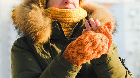 Eine Frau zieht sich draußen Handschuhe an - Foto: iStock/invizbk