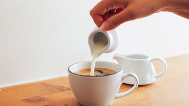 In den Kaffee wird Milch gegossen - Foto: iStock / agrobacter