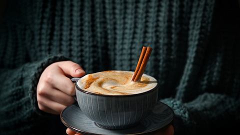 Frau hält Kaffee mit Zimt in der Hand - Foto: iStock/Wirestock
