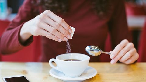 Frau schüttet Zucker in ihren Kaffee - Foto: iStock/Alina Rosanova