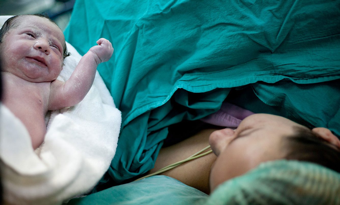 Eine Mutter schaut ihr Baby nach dem Kaiserschnitt an