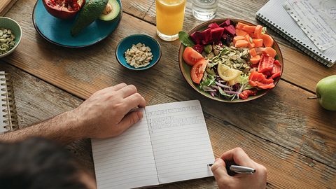 Ein Mann schreibt in sein Ernährungstagebuch - Foto: iStock_KucherAV