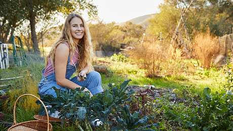 Junge Frau in Latzhose bei der Gartenarbeit - Foto: iStock/Goodboy Picture Company