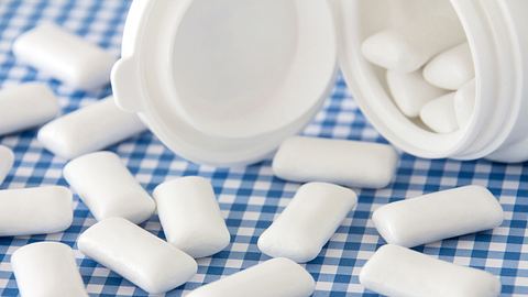 Lose Kaugummis auf blau-weißer Tischdecke, daneben eine weiße Box - Foto: istock / Santje09