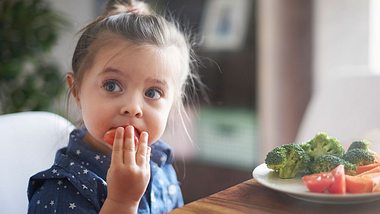 Ein Kind isst eine Tomate - Foto: gpointstudio/iStock