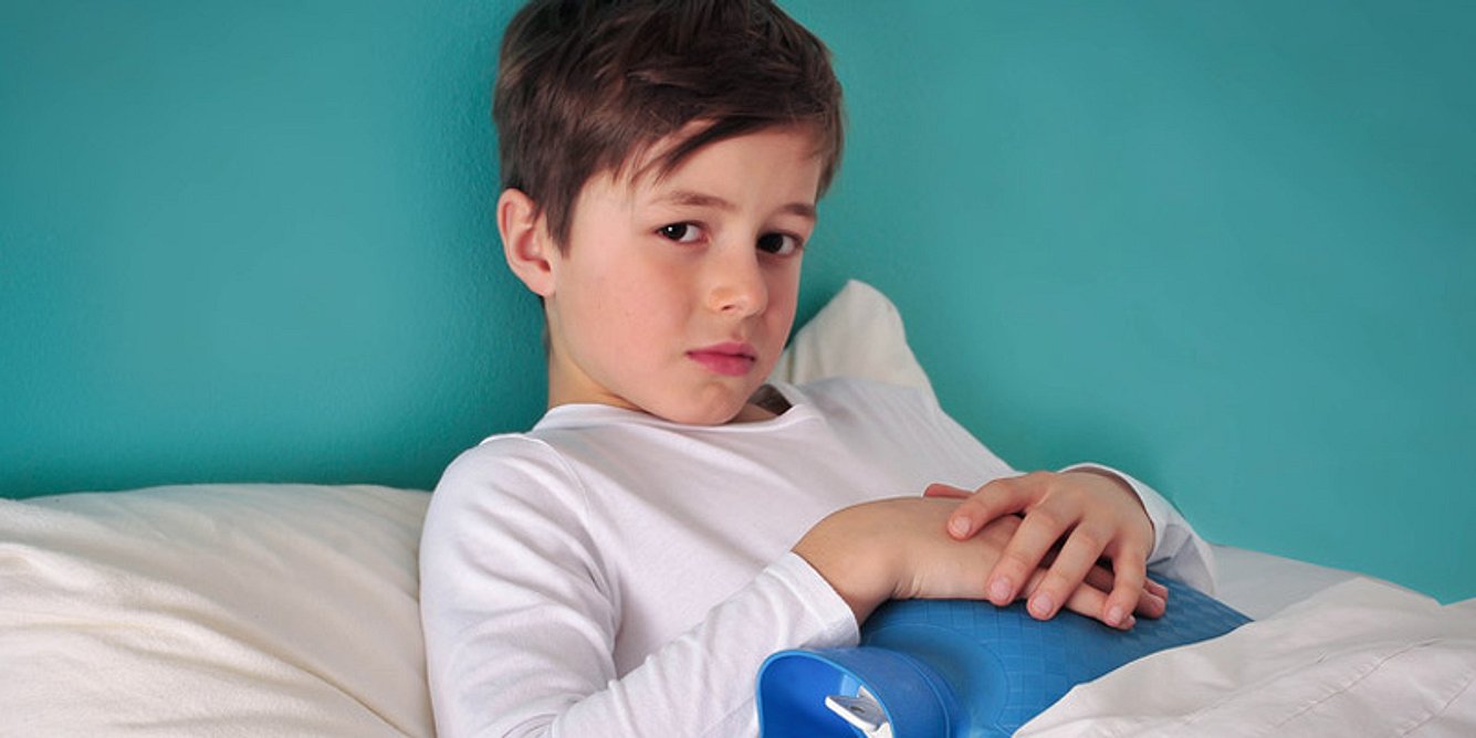 Junge liegt mit Schmerzen im Bett