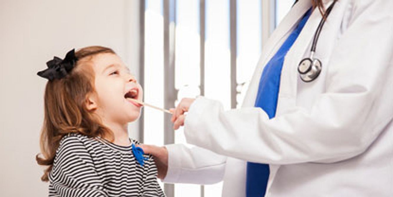 Kinderarzt untersucht den Mund eines Mädchens