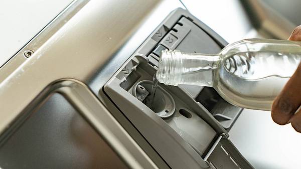 Glasflasche; Flüssigkeit wird in Fach einer Spülmaschine gegeben - Foto: PraxisVita / Vivian Mule