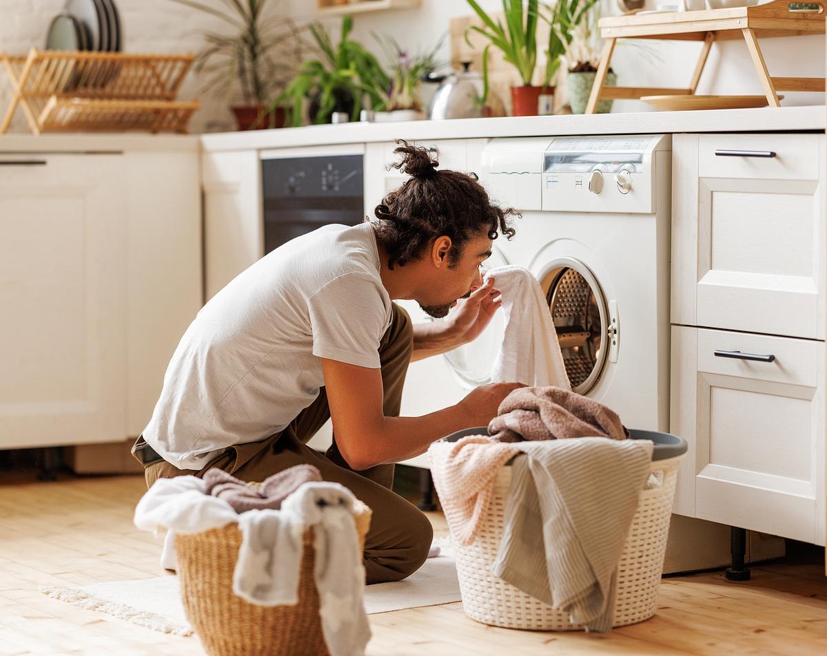 Junger Mann legt Wäsche in die Waschmaschine