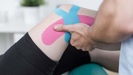 Knie tapen bei einem Patienten - Foto: iStock/KatarzynaBialasiewicz