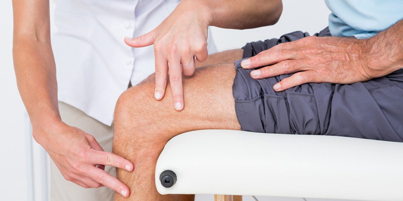 Arzt tastet Knie ab