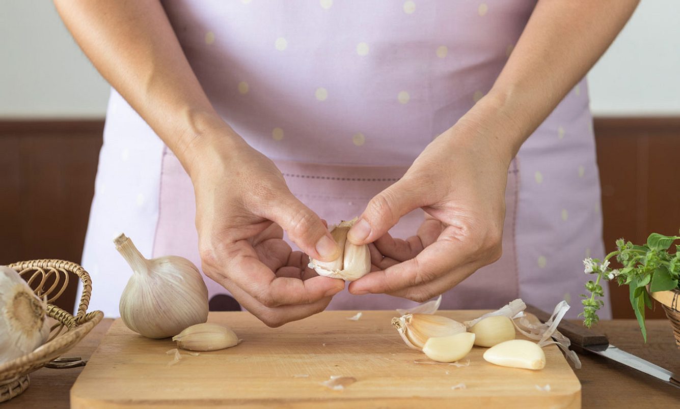 Frau schneidet Knoblauch auf einem Holzbrett