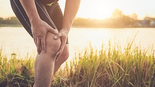 Mann hält sich schmerzendes Knie - Foto: istock/phanuwatnandee