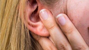 Eine Frau fasst sich ans schmerzende Ohr - Foto: iStock_Animaflora