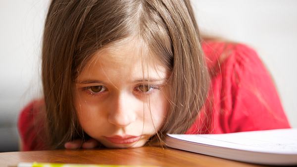 Ein Mädchen stützt das Kinn auf den Tisch - Foto: iStock/princigalli
