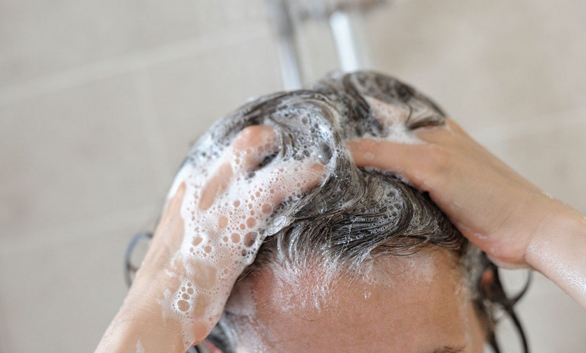Frau wäscht sich Haare mit Shampoo
