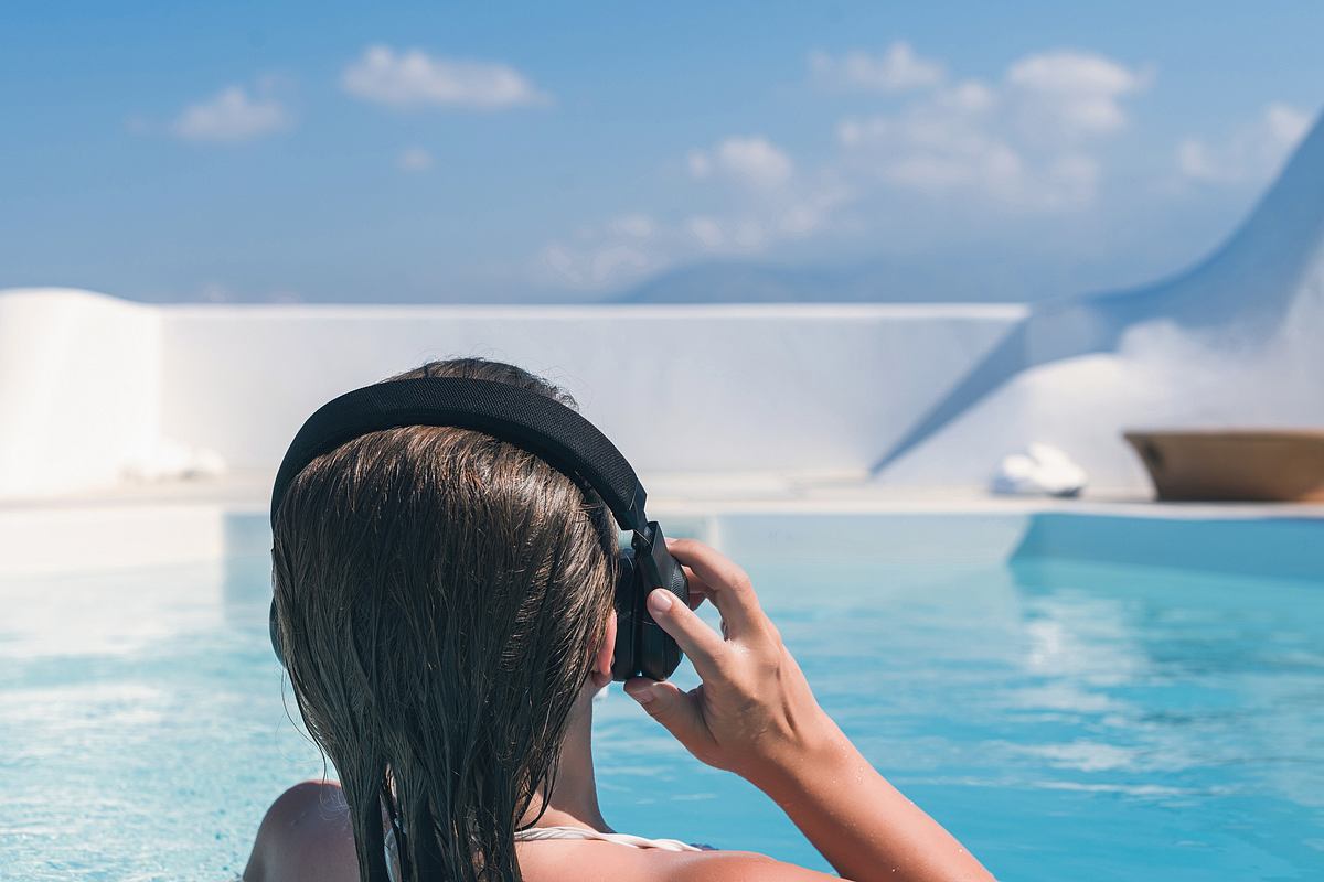 Frau mit Kopfhörern am Pool