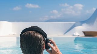 Frau mit Kopfhörern am Pool - Foto: iStock/FTiare