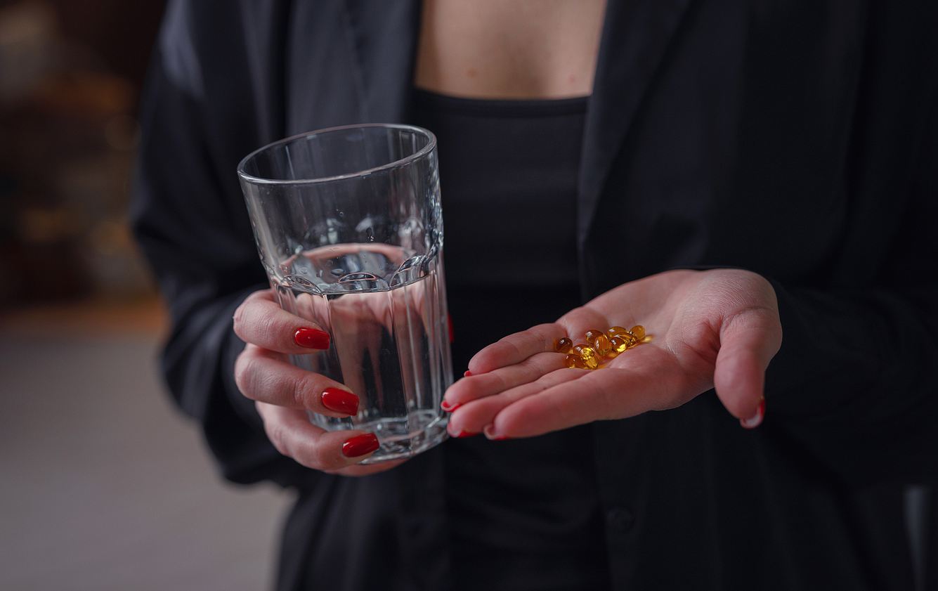 Frau mit Wasserglas und Tabletten in der Hand