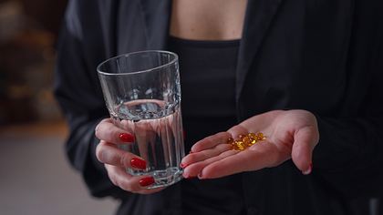 Frau mit Wasserglas und Tabletten in der Hand - Foto: iStock/Santiaga
